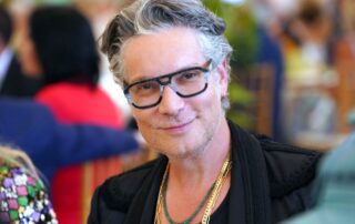 Middle-aged man with gray hair and glasses smiling warmly.