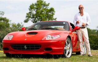 A man standing next to a red sports car.