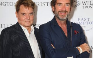 Two men standing next to each other on a red carpet.