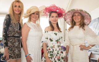 Four women posing for a photo wearing hats.