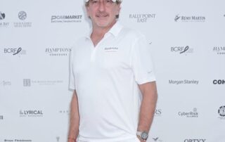 A man in a white shirt standing on a red carpet.