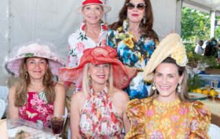 A group of women in floral hats posing for a photo.