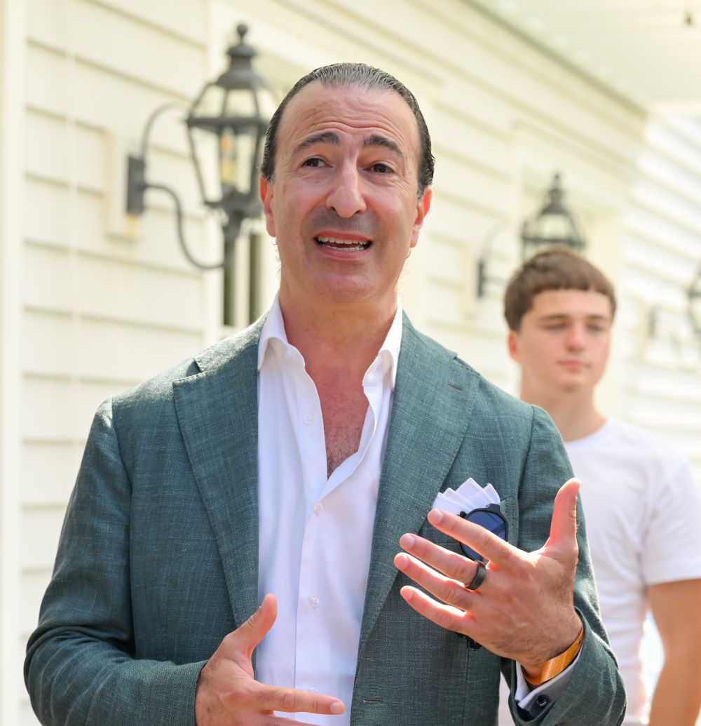 Young man with a slight smile against a gray background.