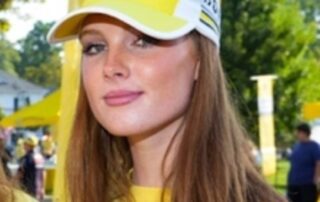 Woman in yellow shirt and hat smiling.