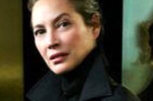 A woman in a black turtleneck and coat.