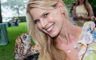 Woman smiles holding a small owl.