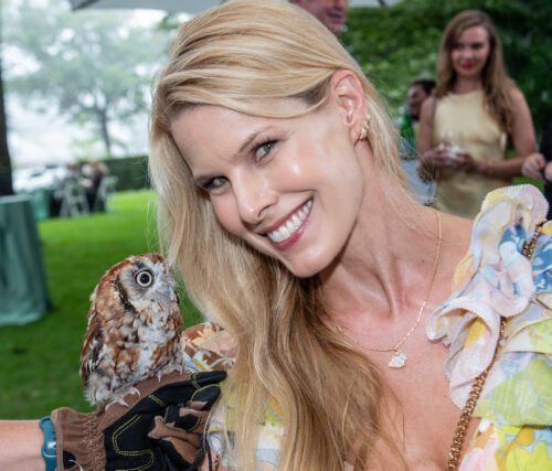 Woman smiles holding a small owl.