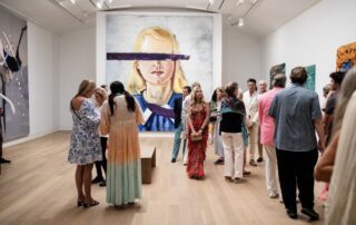 Group of people viewing artwork in gallery.