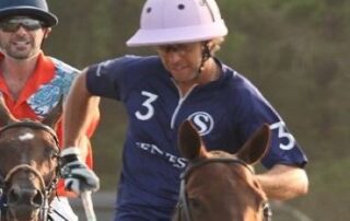 Polo player in pink helmet riding horse.