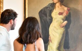 Couple admiring a painting of a woman.