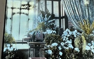Sunroom with flowers and antique furniture.