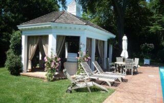 White gazebo with patio furniture near pool.