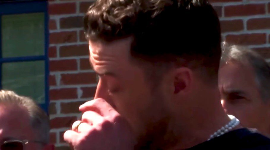 Young man with a slight smile against a gray background.