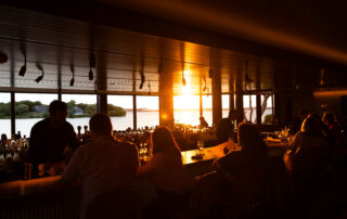 People enjoying sunset views inside a cozy bar with warm lighting.