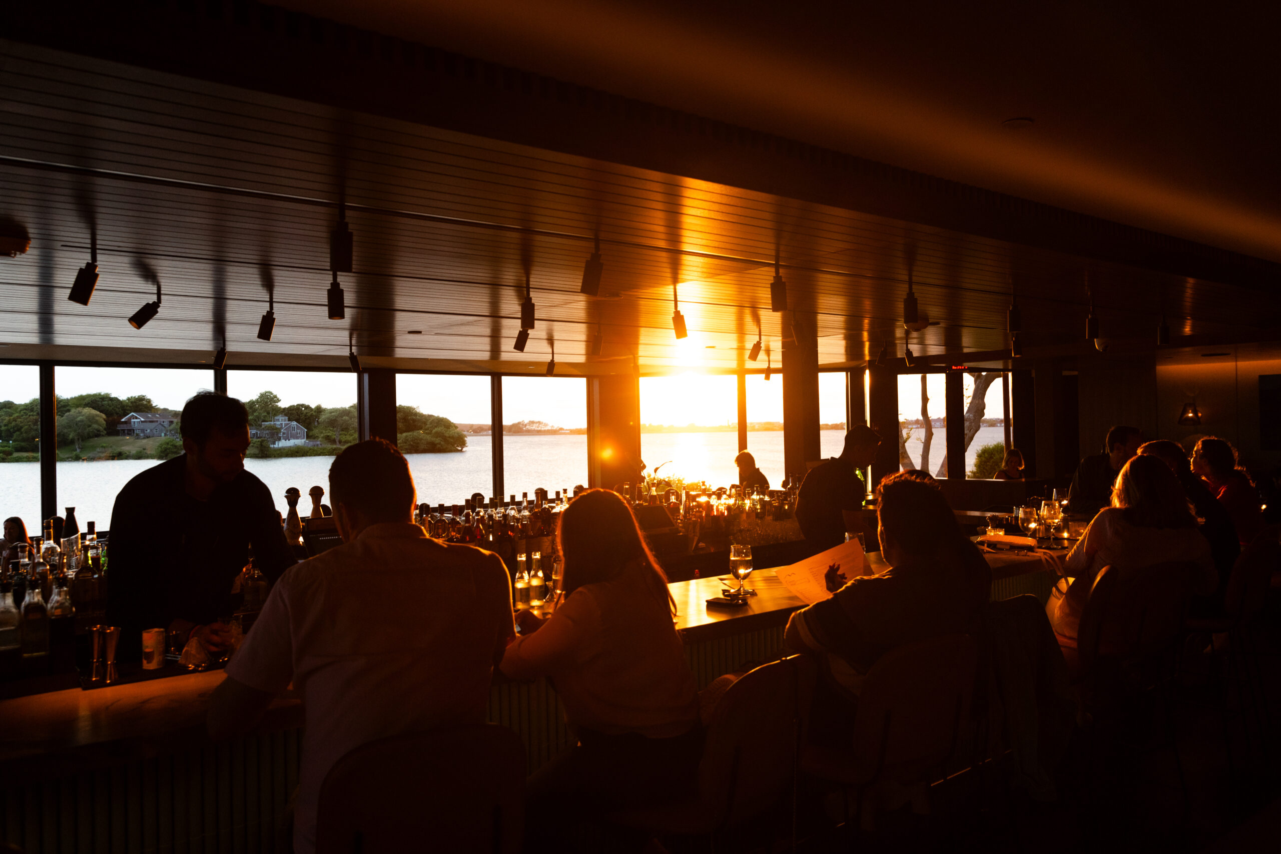 People enjoying sunset views inside a cozy bar with warm lighting.