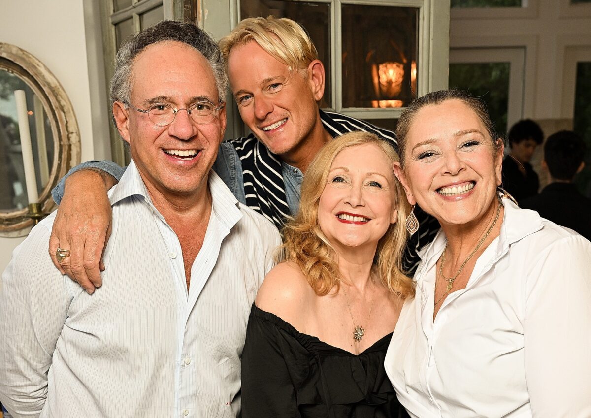 Four adults smiling together indoors, showing warmth and friendship.