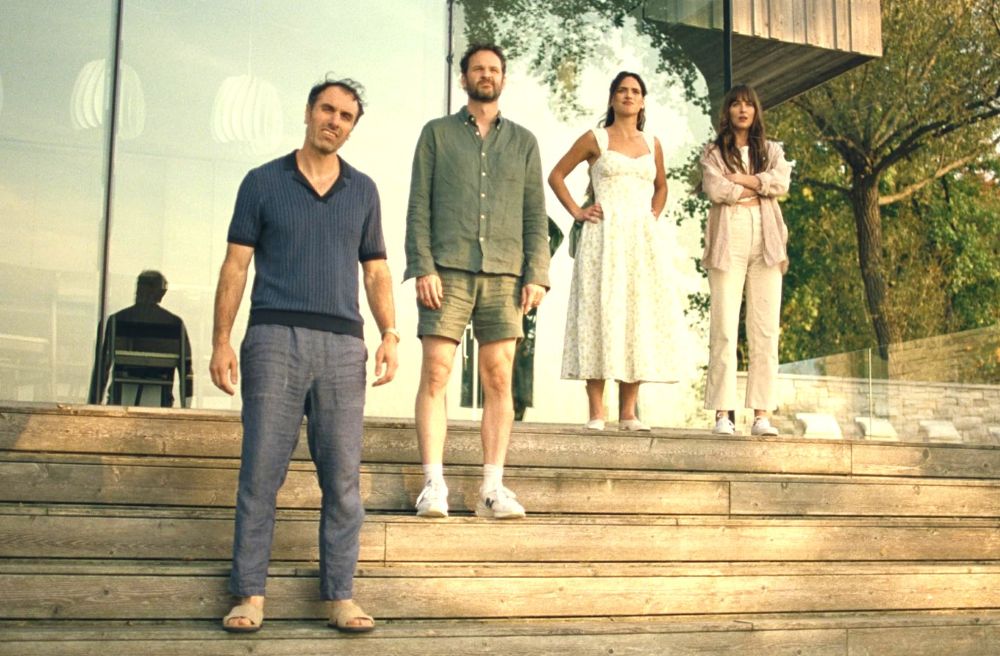 Four people standing on outdoor steps, dressed casually and looking forward.