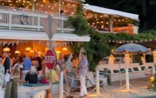 Evening gathering at a lively, warmly lit outdoor restaurant with people socializing.
