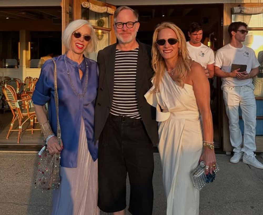 Three stylishly dressed adults posing outdoors in evening light.