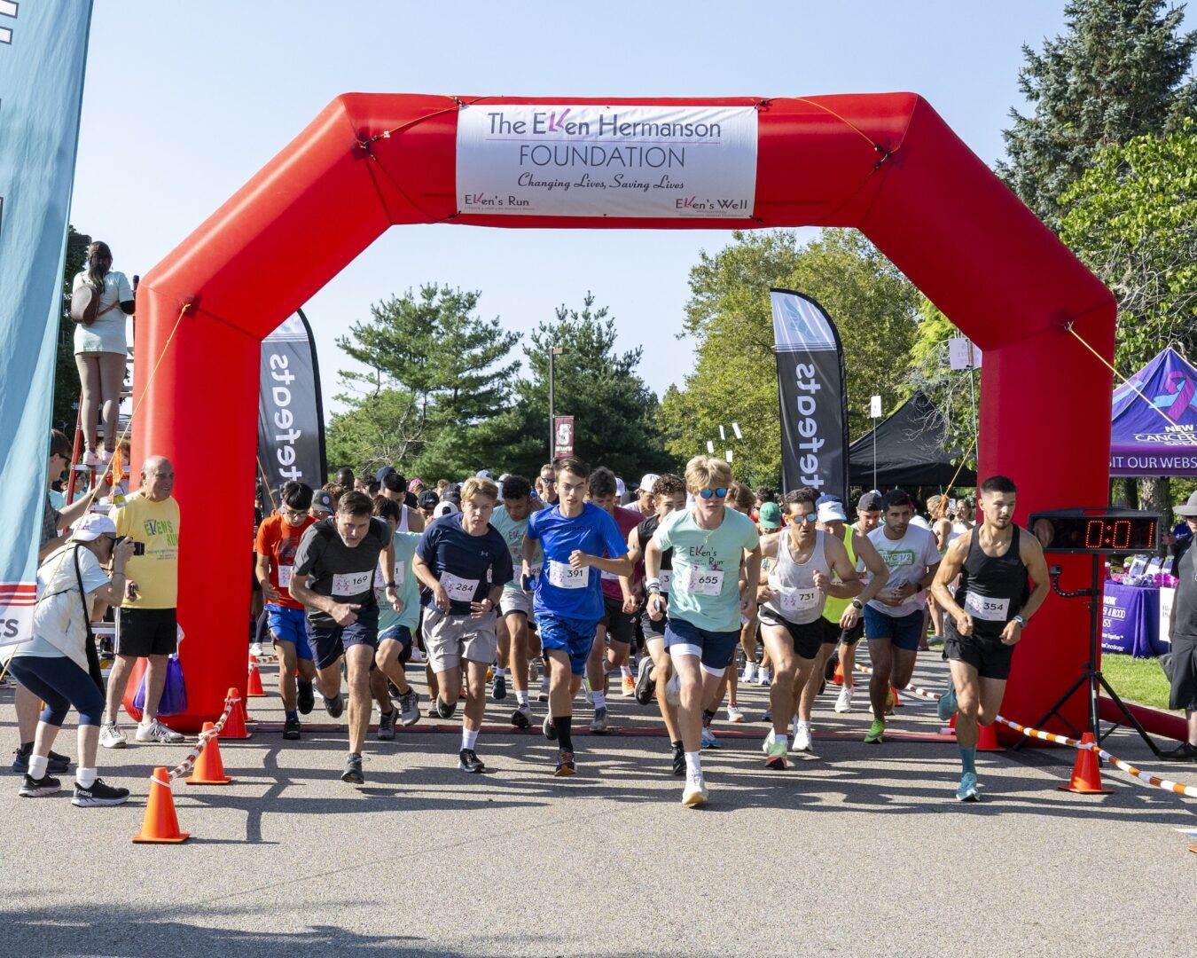 Runners start a charity race under a red inflatable arch.