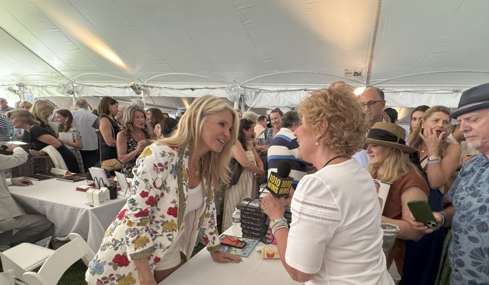 Two women engaged in a lively interview under a tent at an event.