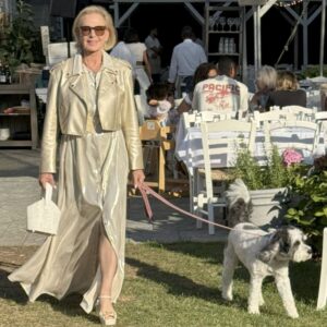 Woman in elegant gold outfit walking a dog outdoors.