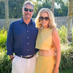 A smiling couple wearing sunglasses outdoors in a sunny garden.