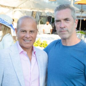 Two men posing together outdoors at a social event.