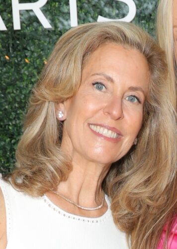 Smiling woman with blonde hair and pearl earrings.