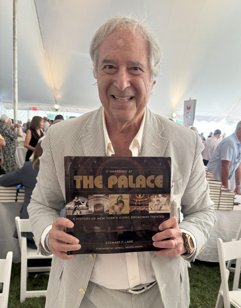 Man smiling while holding a book about The Palace nightclub.