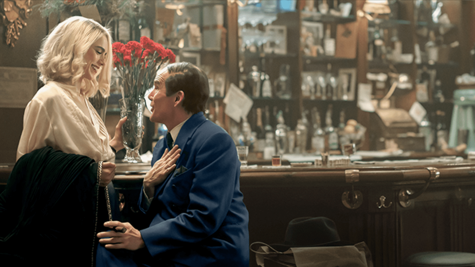 Man in blue suit passionately talks in a vintage bar setting.