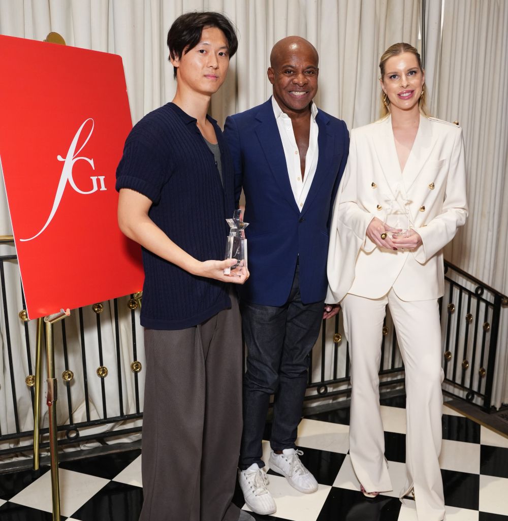 Three people posing at an event, holding awards.
