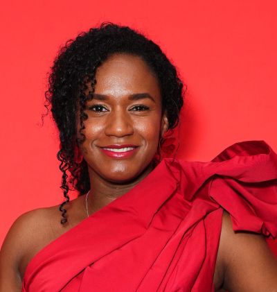 Woman smiling in a vibrant red dress against a red background.