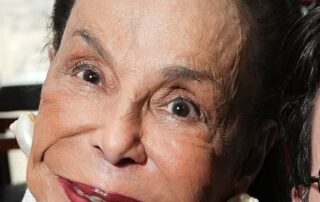 Close-up of an elderly woman smiling warmly at the camera.